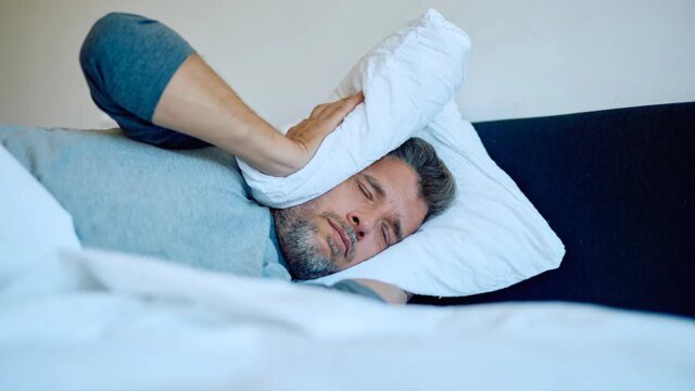 man-covers-his-ears-with-pillow.jpg