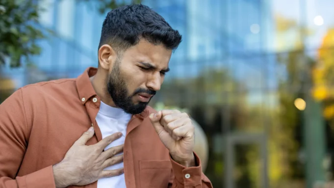 man-coughing-outside-building.webp