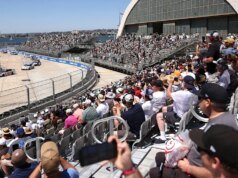 在聖地牙哥科羅納多海軍基地舉行的 NASCAR 紅旗比賽中,一名車迷跳過柵欄與車手會面。